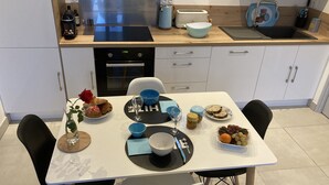 Une cuisine moderne avec une table à manger dressée pour deux personnes, où l’on peut déguster une variété de plats et de boissons.