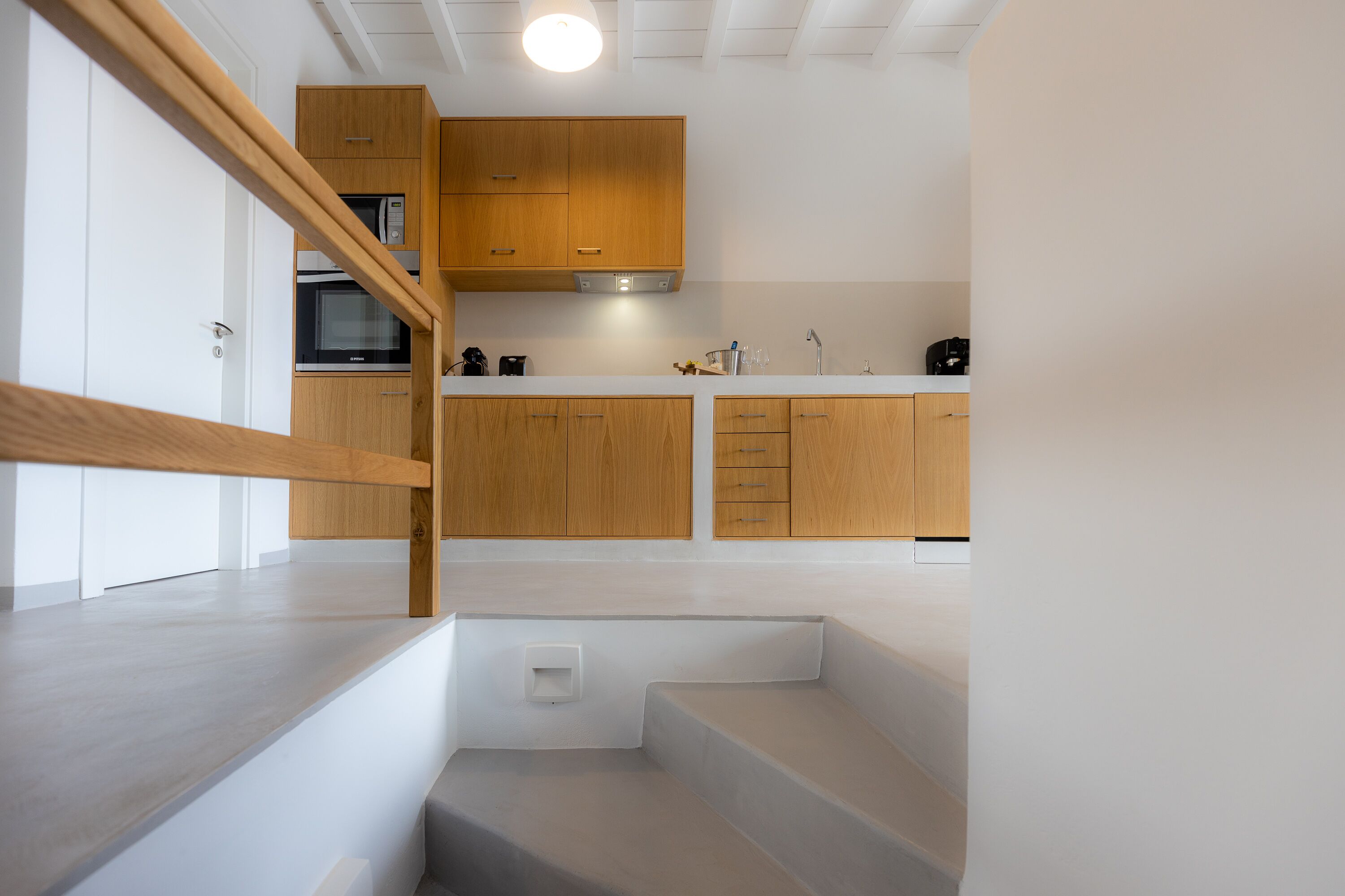 Una cocina moderna con armarios de madera, un microondas integrado y una encimera blanca.