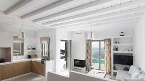Uma sala de estar moderna com sofá, televisão e vista para o mar.