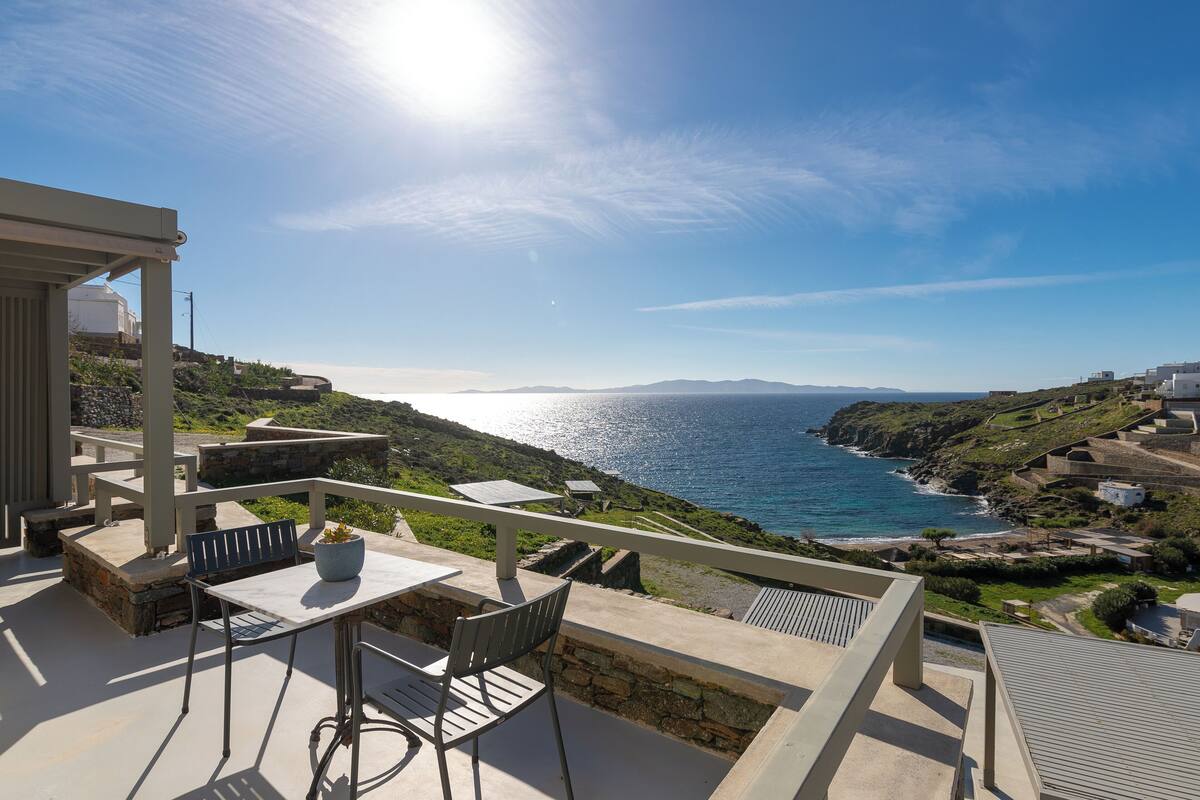 Une terrasse avec une table et des chaises donnant sur un paysage côtier.
