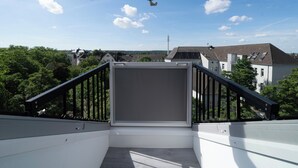Varanda com teto de vidro, oferecendo vista para edifícios residenciais e árvores.