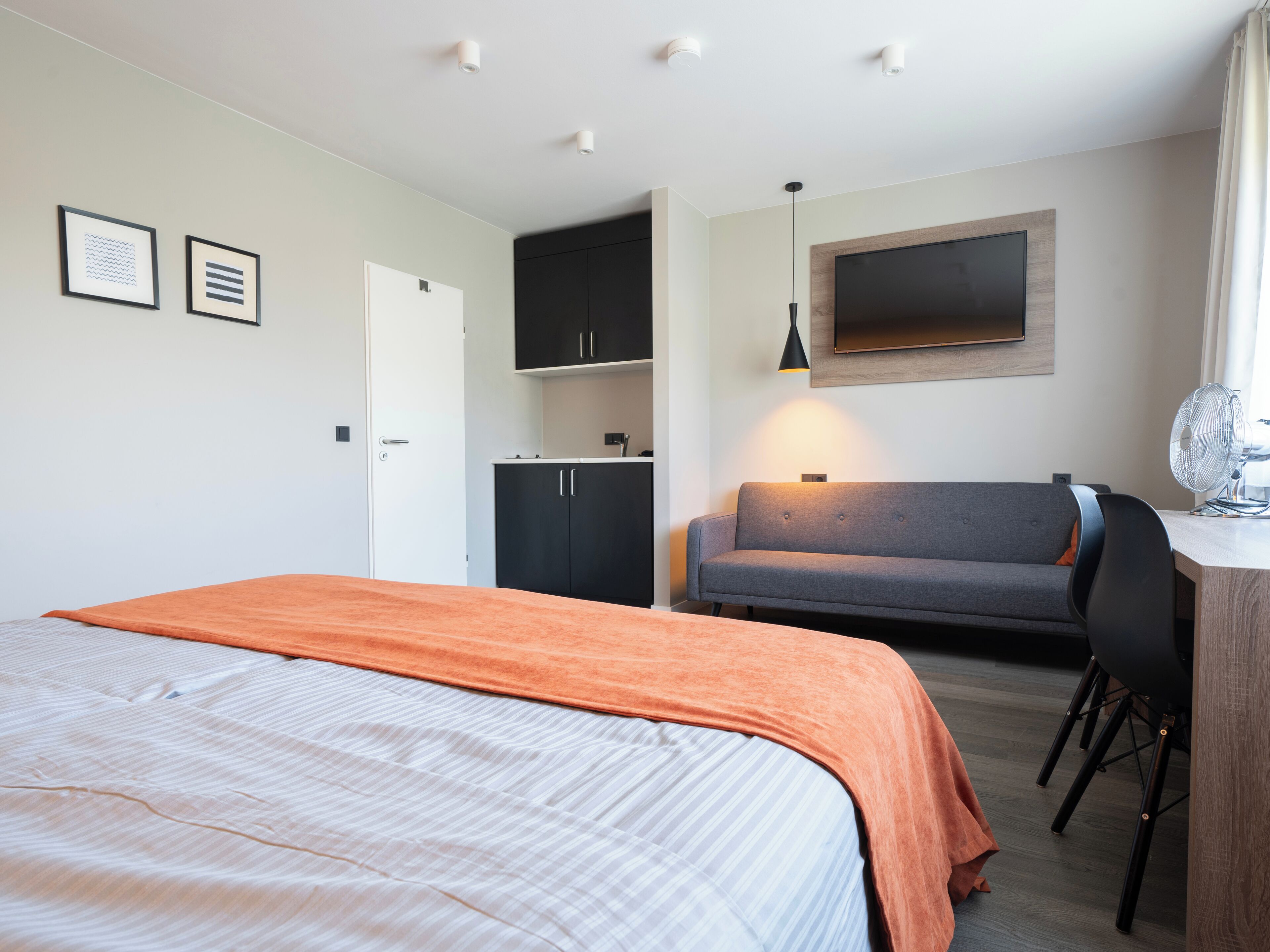 Ein Hotelzimmer mit Bett, einer Couch, einem Schreibtisch und einem Fernseher.