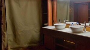 Habitación con carpa, piso de madera, dos lavamanos y un espejo sobre ellos.