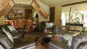 Sala de estar con sofás de cuero, una mesa de centro y una zona de bar con botellas.