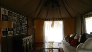 Una sala de estar con un sofá, una mesa de centro de vidrio, una chimenea y una pared decorada con fotografías.