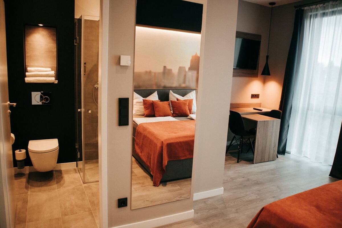 Une chambre d’hôtel comprenant un lit, un bureau, une chaise, des toilettes et un espace douche.
