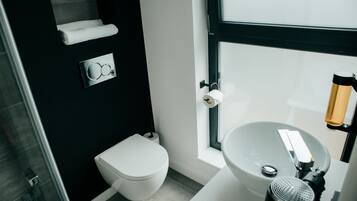 Un baño moderno con inodoro blanco, un lavamanos grande y un perchero para toallas.