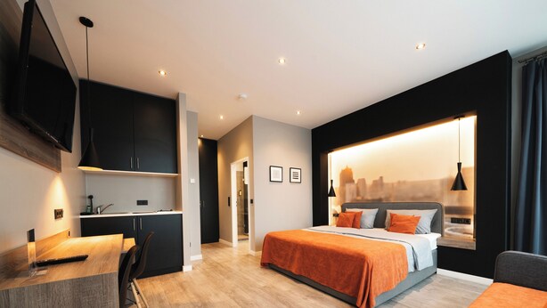 A modern hotel room with a bed, a desk, and a city view. - JustStay Grevenbroich Hotel & Apartments (Grevenbroich)