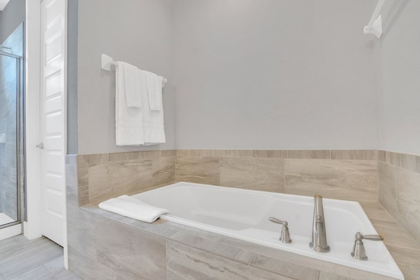 Un baño moderno con una bañera independiente, un perchero para toallas y un box de ducha de vidrio.