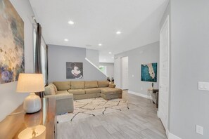 Una sala de estar moderna con un sofá modular, una lámpara y obras de arte en las paredes.