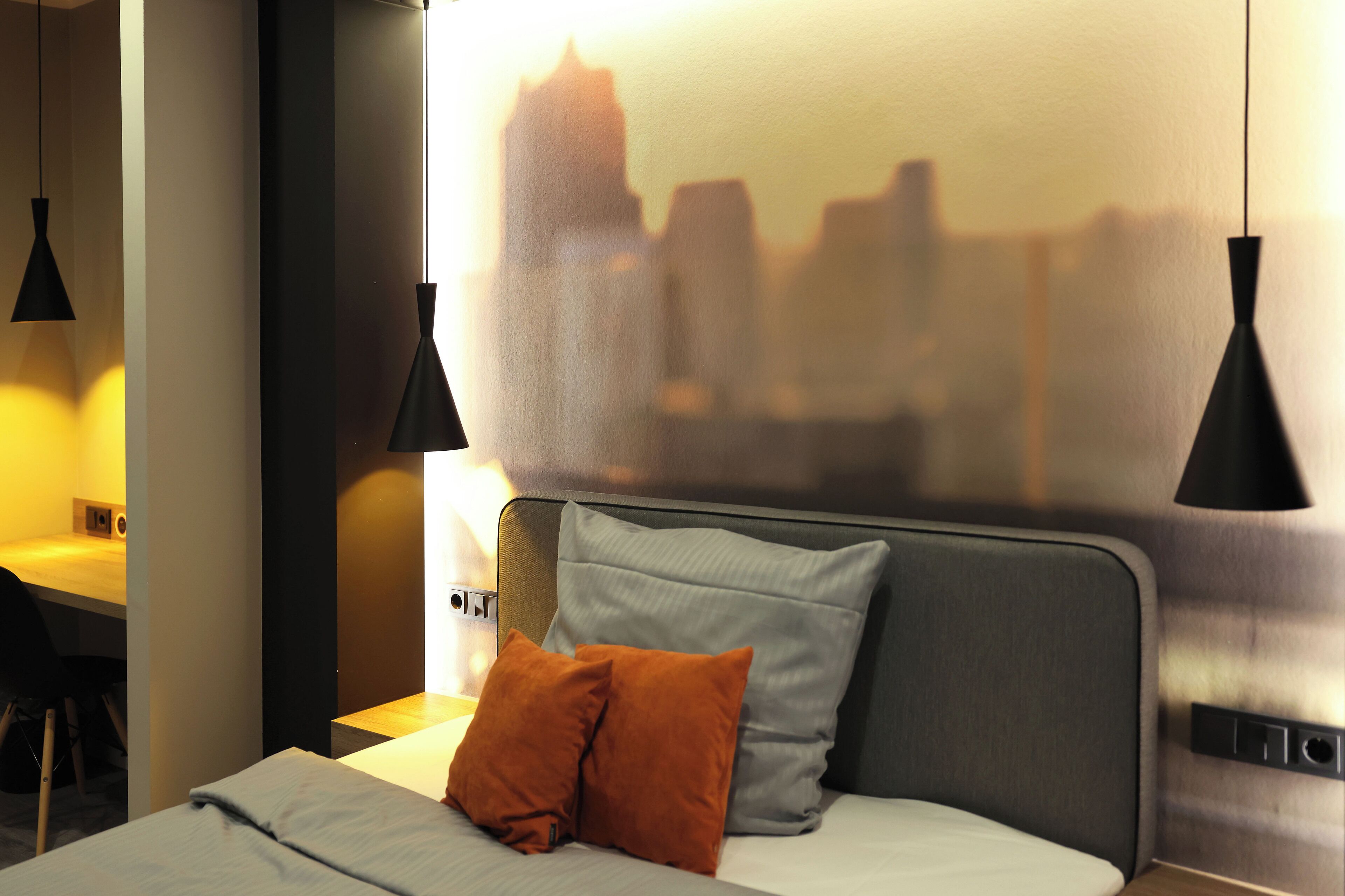 Una habitación de hotel con cama, dos almohadas, un escritorio y una silla.