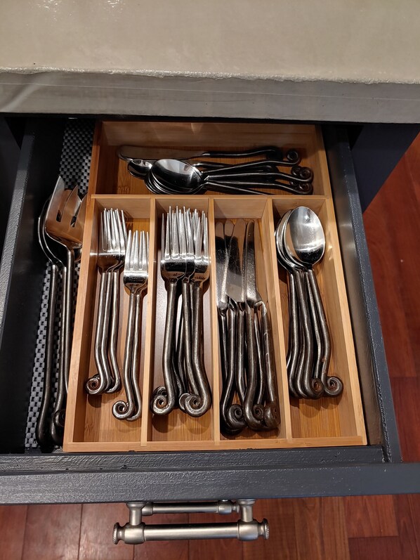 Un cajón con cubiertos ordenados, incluyendo tenedores, cucharas y cuchillos.