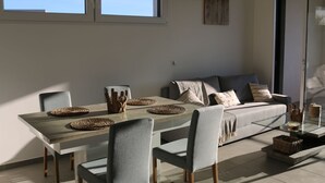 Ett modernt matområde med ett träbord, grå stoppade stolar och en grå soffa.