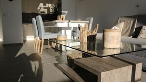 Ett modernt vardagsrum med ett soffbord i glas, ett sidobord i trä och en soffa.