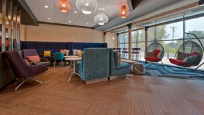A modern lounge area with seating options including a sofa, chairs, and a hanging chair.