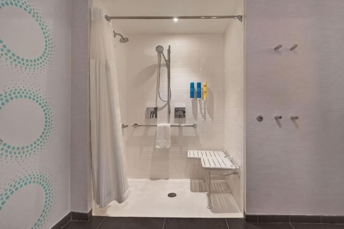 A shower area with a glass door, a towel rack, and a shelf with toiletries.