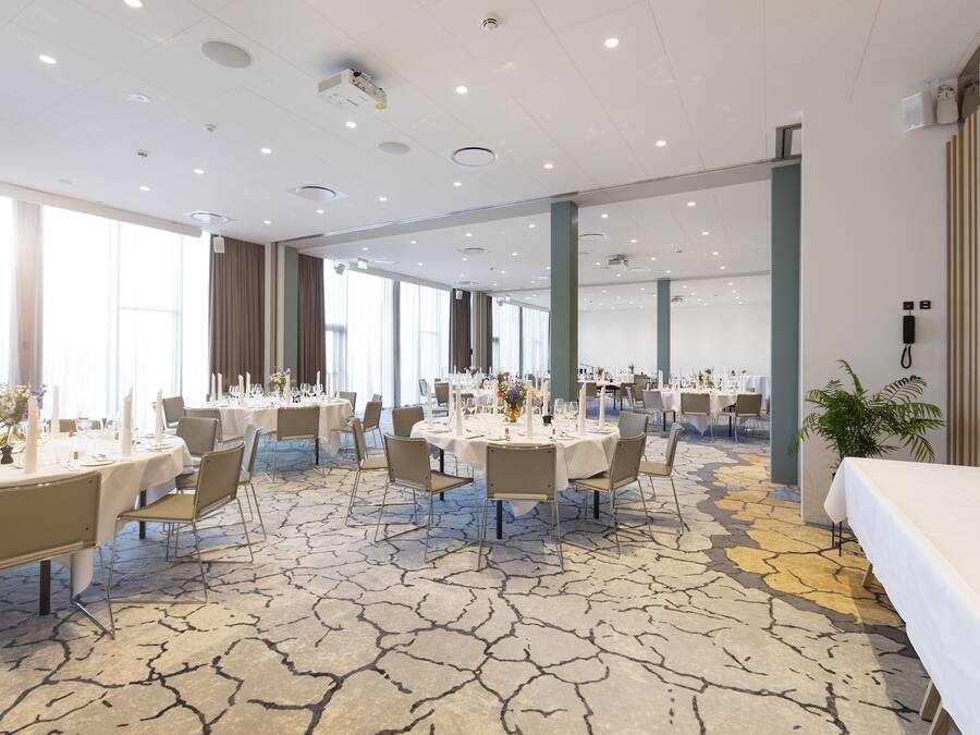 A spacious conference room with round tables, chairs, and a patterned carpet.