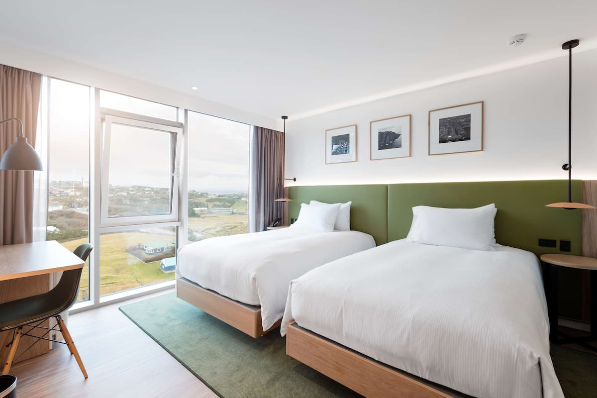 Una habitación de hotel con dos camas, un escritorio y vistas a la ciudad.