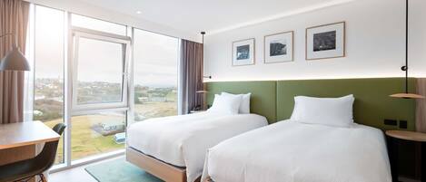 Una habitación de hotel con dos camas, un escritorio y vistas a la ciudad.
