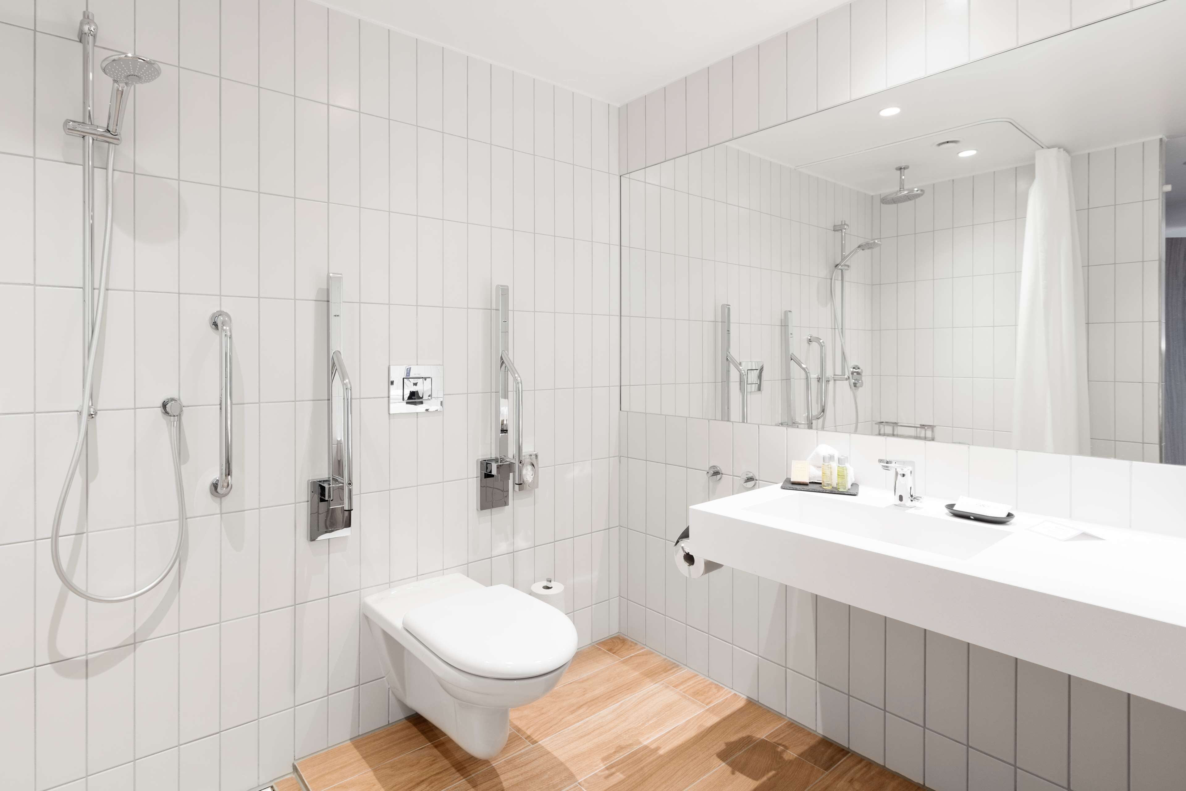A modern bathroom with a white sink, a toilet, and a shower with multiple heads.