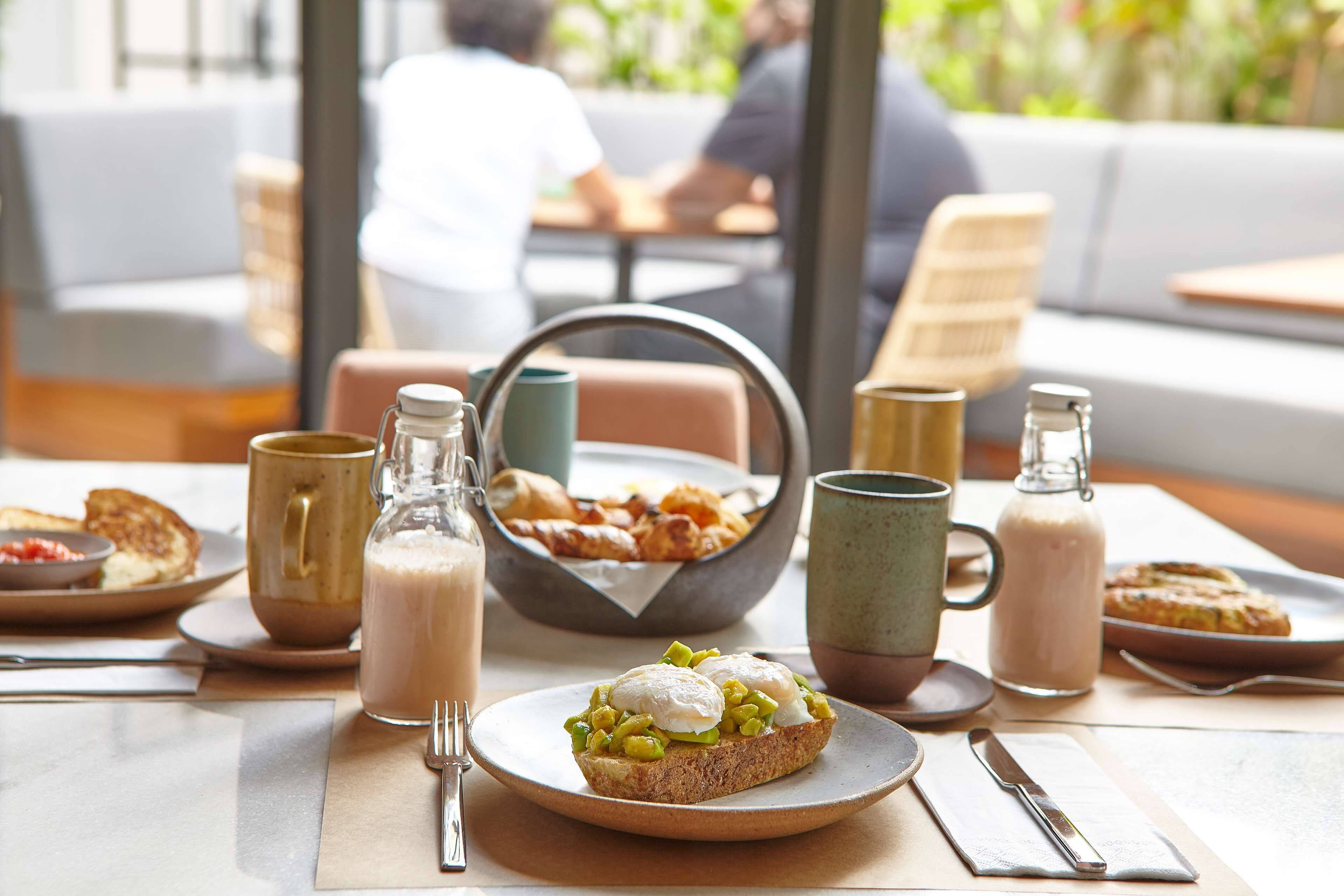 A breakfast setting with a variety of food items, including toast with eggs, a bowl of pastries, and a bottle of milk.