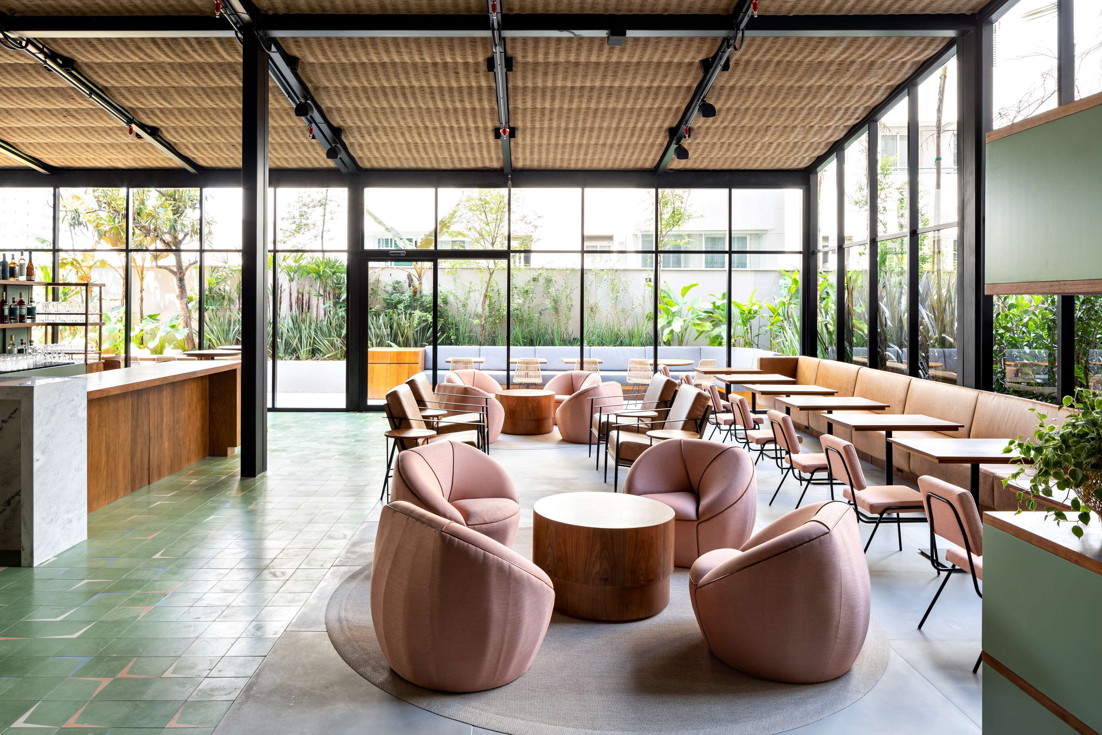 Een modern café met ronde tafels en stoelen, een bar en grote ramen met uitzicht op het omliggende landschap.