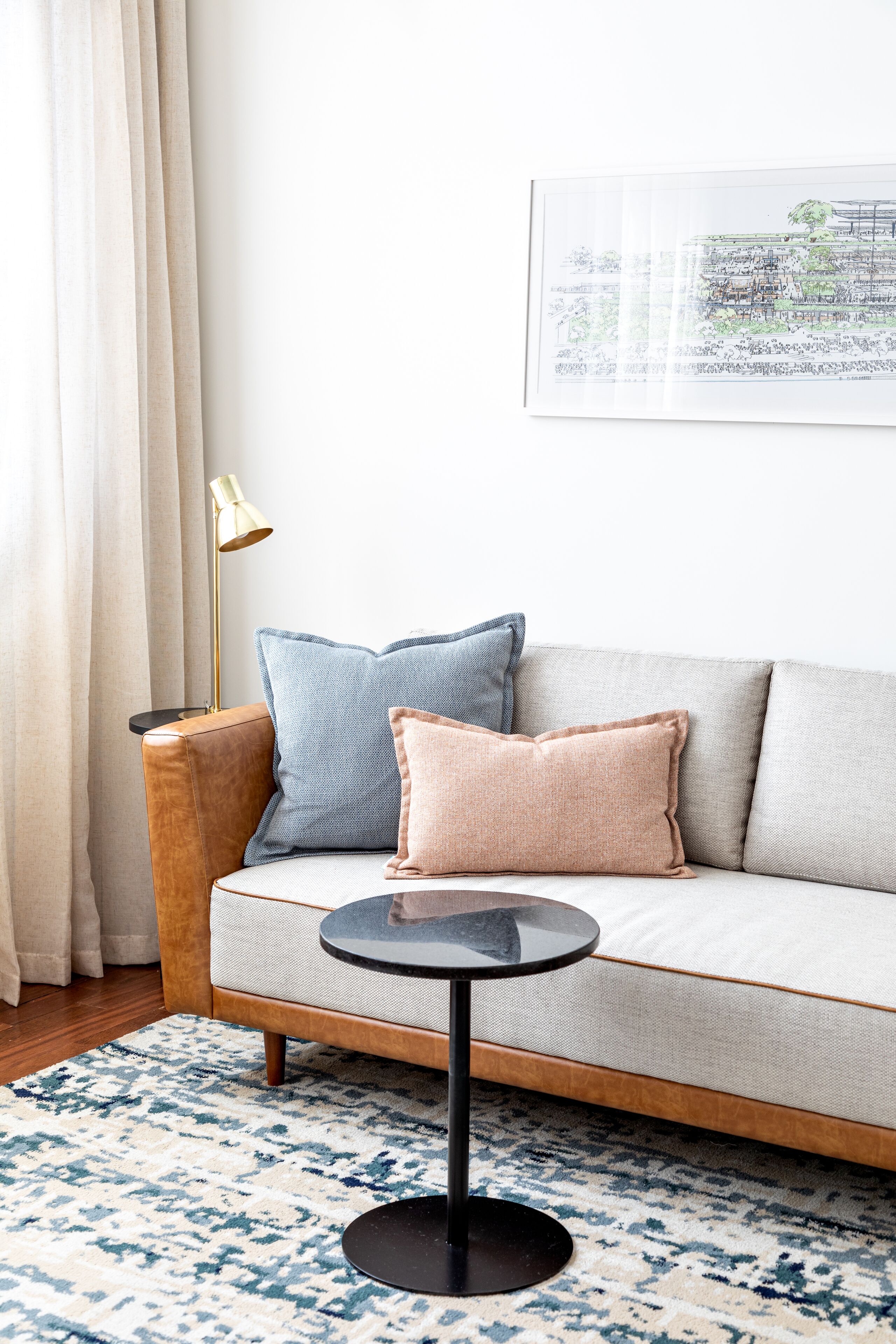 Un salon moderne avec un canapé, une petite table ronde et une lampe.