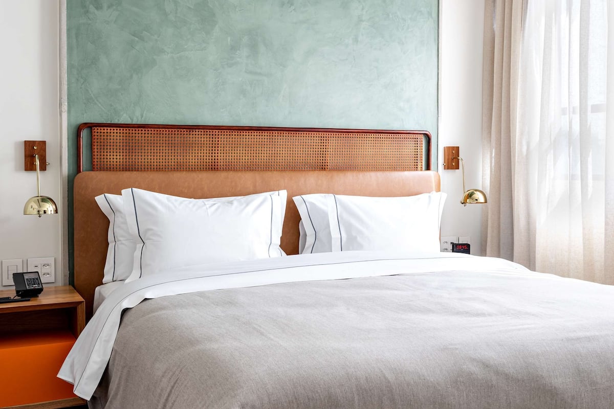 Una habitación de hotel moderna con una cama grande, un cabecero de madera y una pared de acento verde.