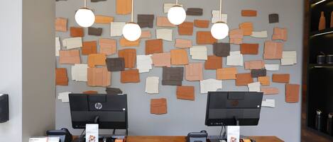 A reception desk with two HP monitors, a wooden counter, and a wall decorated with variously sized, colored paper cutouts.