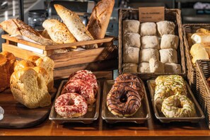 Diversitat de pa, ensaïmades i donuts exposats en safates i cistells.
