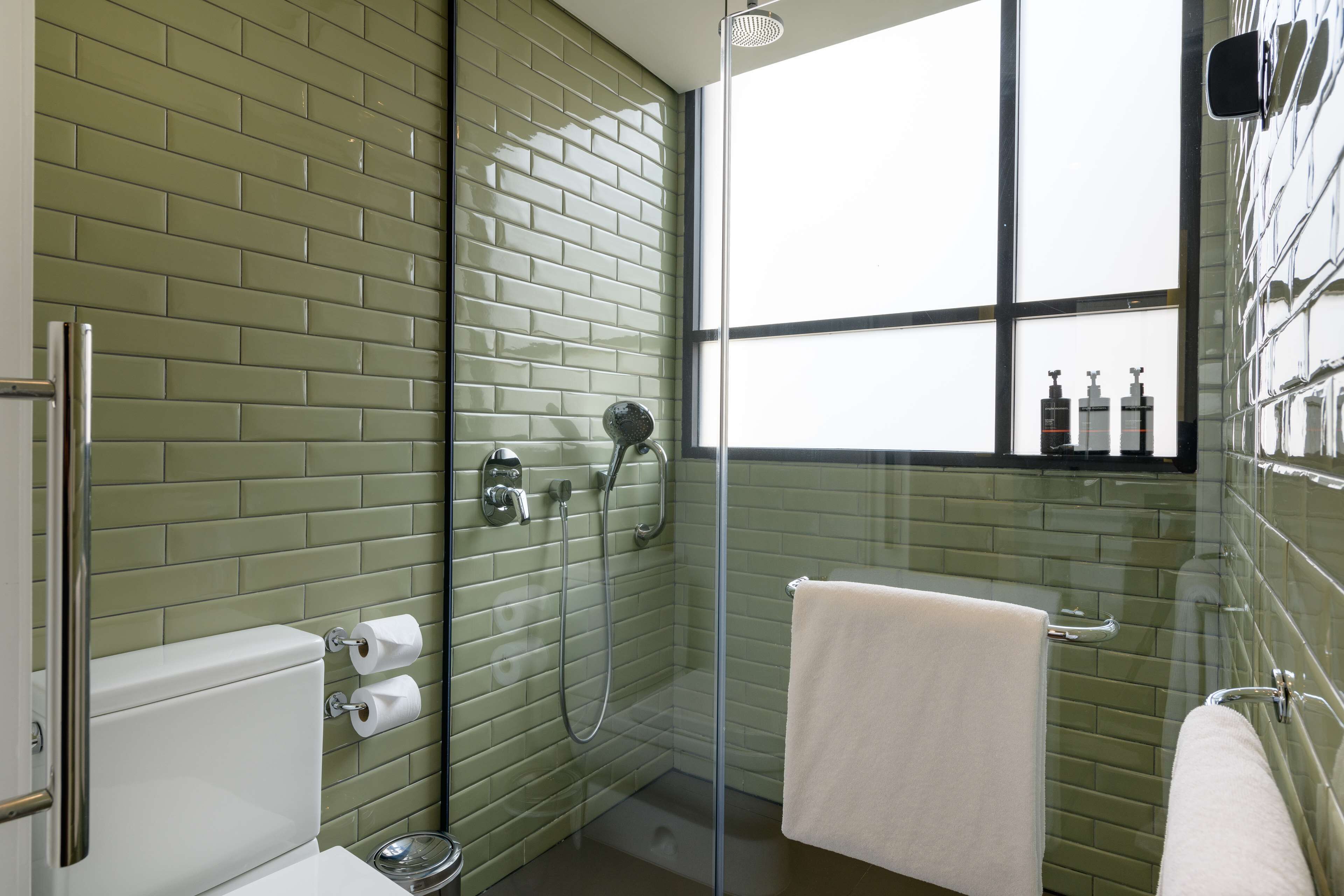 Een badkamer met een douchecabine van glas, een toilet en een wastafel.