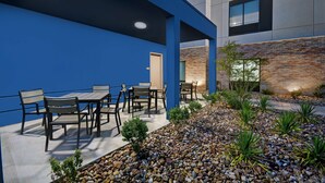 Un patio al aire libre con pared azul, pared de ladrillo y zona de grava con plantas pequeñas.