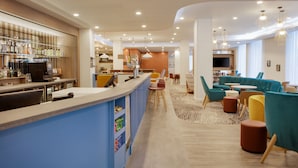 A modern bar area with a counter, seating area with sofas and chairs, and a television.