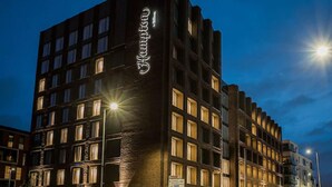 Un hotel moderno con un llamativo letrero que dice 'Famous' en la fachada, varios pisos y vista a la calle bajo un cielo despejado.