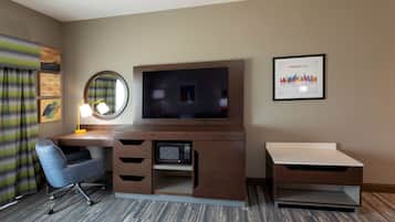 Quarto de hotel com escrivaninha de madeira, televisão, micro-ondas, cadeira e quadro com imagem de Minneapolis.