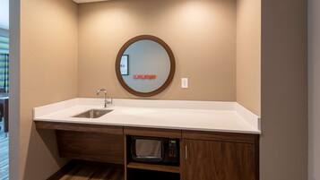 A compact kitchenette with a sink, microwave, and a small cabinet.