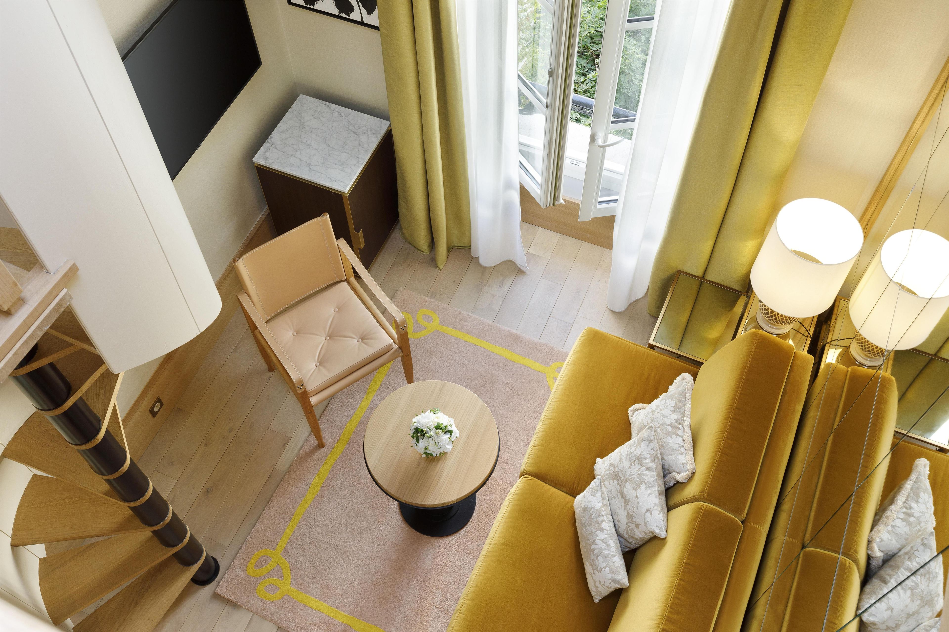 A modern living room with a sofa, a small round table, a chair, and a view of the outdoors through a window.
