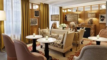 A well-appointed lounge area with plush seating, a marble coffee table, and a decorative fireplace.