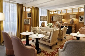 Eine stilvoll eingerichtete Lounge mit bequemen Sitzmöglichkeiten, einem Marmor-Couchtisch und einem dekorativen Kamin.