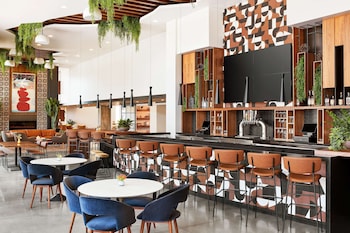 A modern living room with a grey sofa, a round coffee table, and a dining area with a table and chairs. at Canopy by Hilton Tempe Downtown