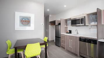 Una cocina moderna con comedor, electrodomésticos de acero inoxidable y un cuadro en la pared.