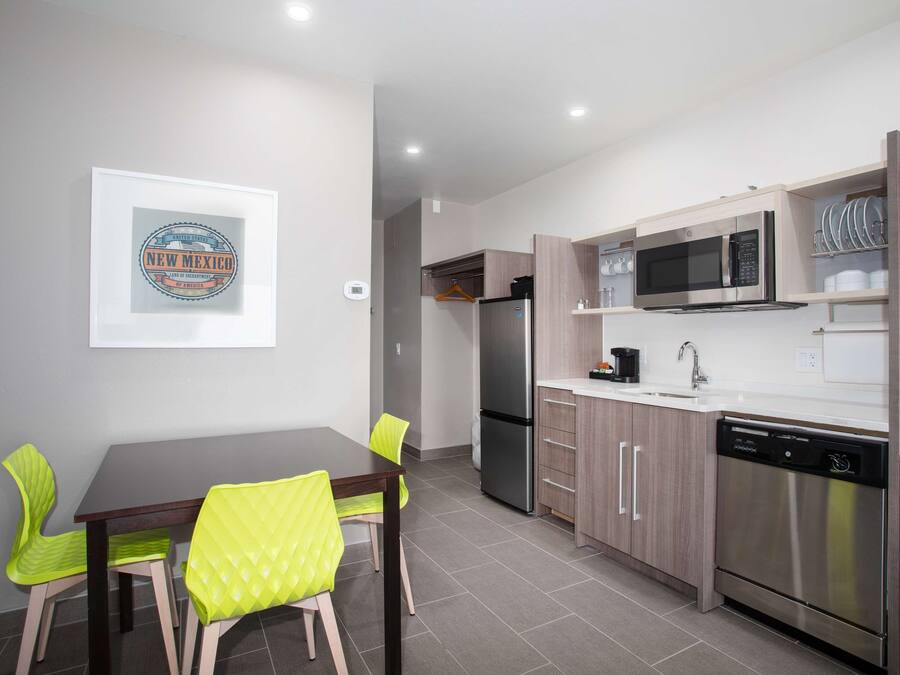 Una cocina moderna con comedor, electrodomésticos de acero inoxidable y un cuadro en la pared.