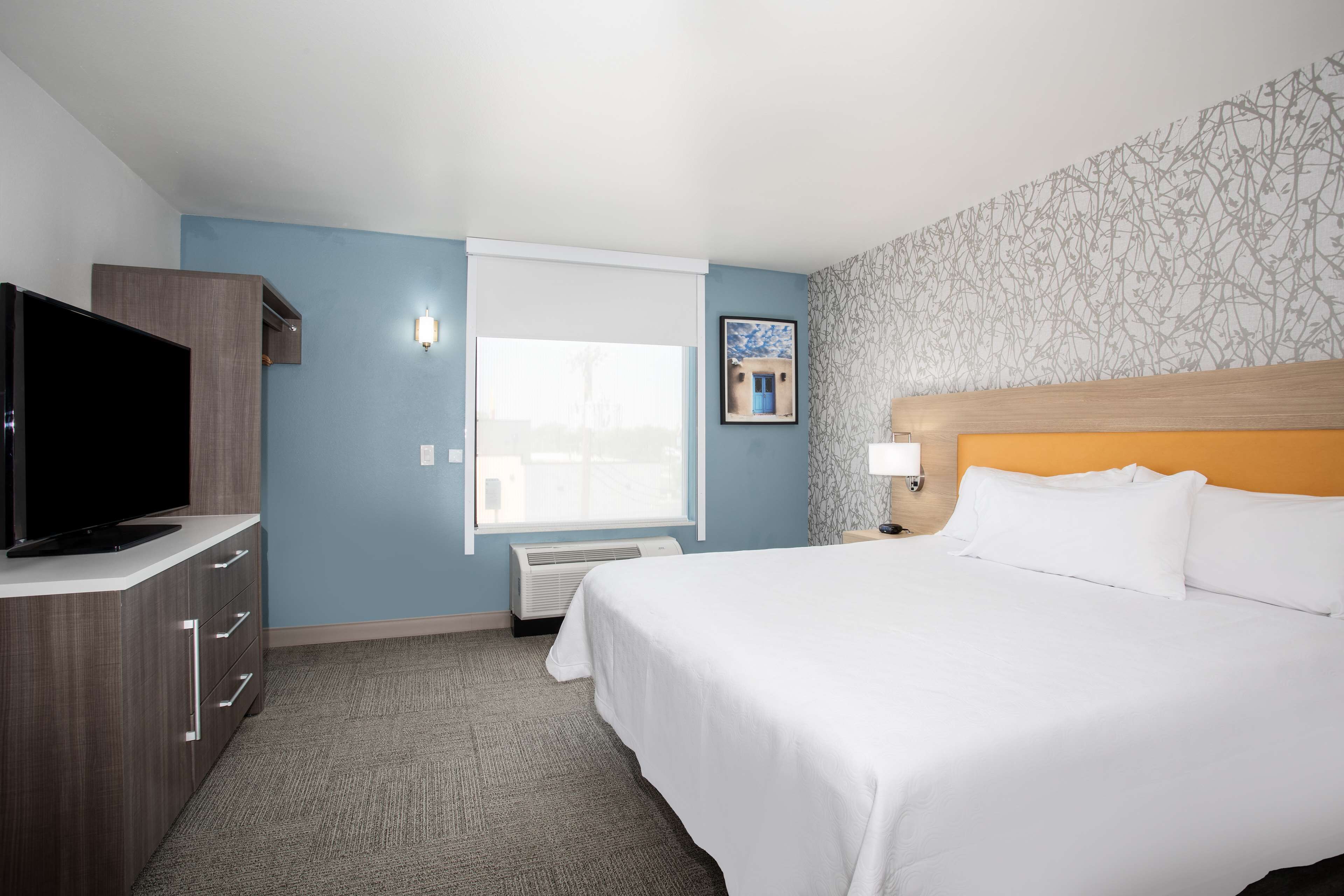 Une chambre d’hôtel avec un lit, une télévision, un bureau et une fenêtre.
