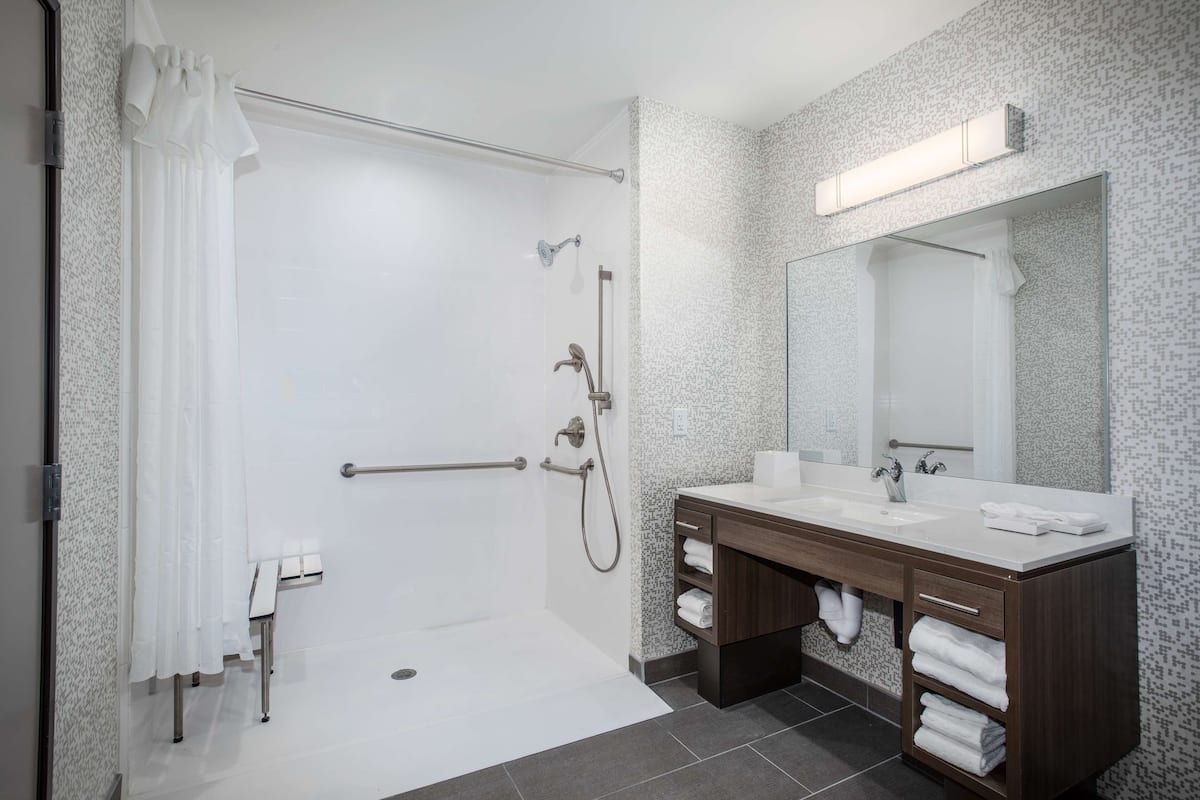 A modern bathroom with a walk-in shower, a double sink vanity, and a large mirror.