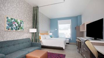 Une chambre d’hôtel avec un lit, un canapé, un bureau, une télévision et une fenêtre.