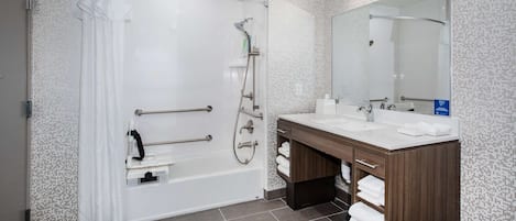 A modern bathroom with a bathtub, shower, and dual sinks.