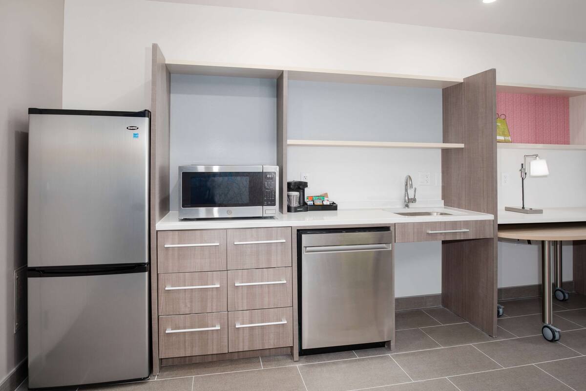 A modern kitchen with a stainless steel refrigerator, microwave, and dishwasher.