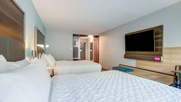 Quarto de hotel com duas camas, televisão e banheiro visível por uma porta aberta.
