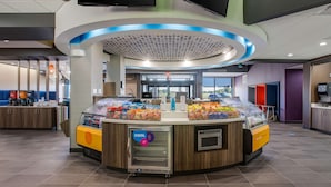 Een moderne, zelfbedieningskiosk met een gekoeld display, een koffiehoek en een balie met snacks.
