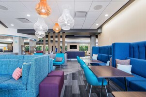 Un moderno vestíbulo de hotel con zonas de estar azules, un mostrador de recepción e iluminación contemporánea.